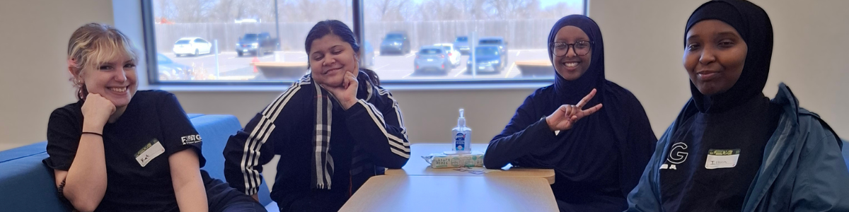 Students wearing first-gen gear smile while gathered at a table.