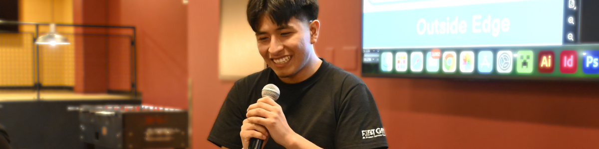 A student smiles while holding a microphone.